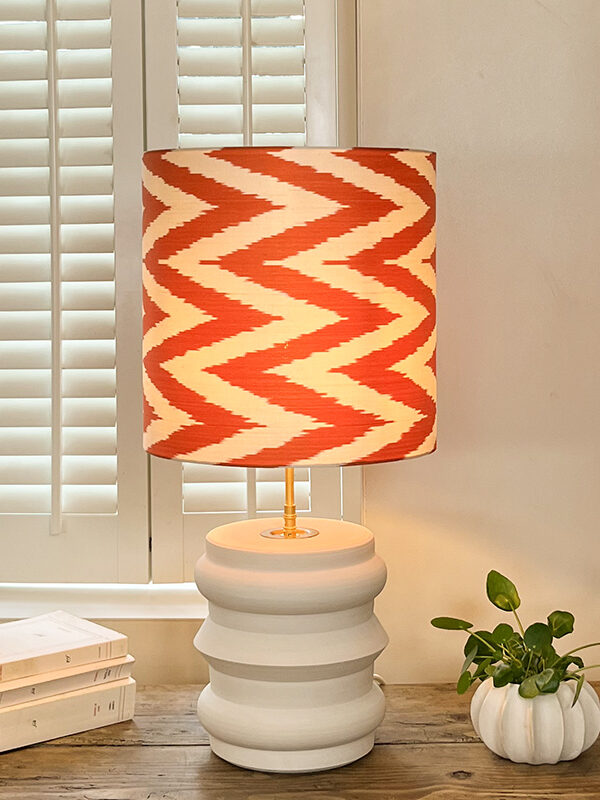Lampe en faïence allumée avec abat-jour orange à chevrons – Modèle Capucine