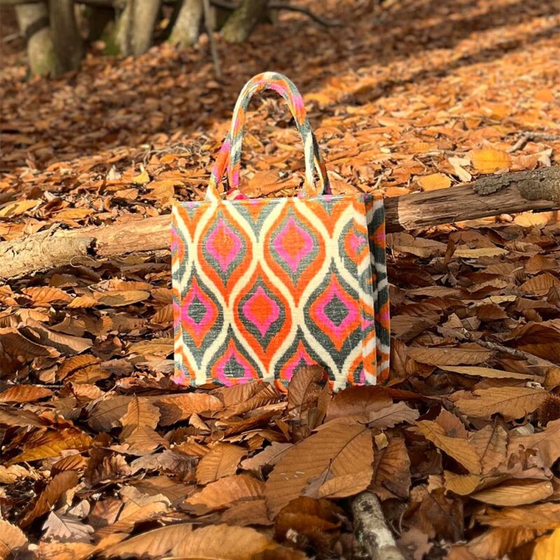 Cabas en velours Boho rose orangé posé sur des feuilles en forêt à l’automne