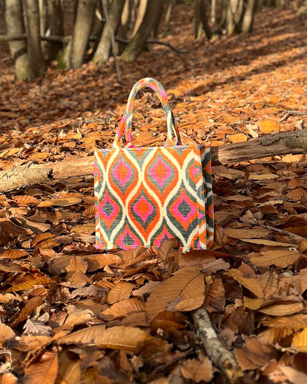 Cabas en velours Boho rose orangé posé sur des feuilles en forêt à l’automne