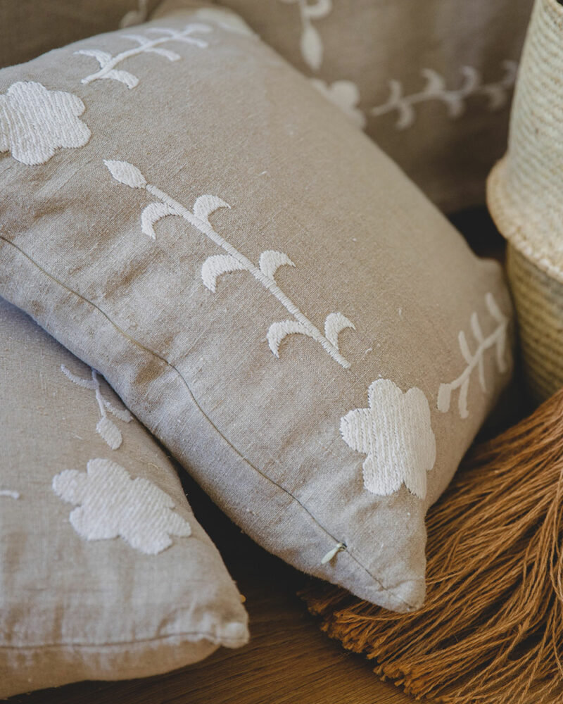 Coussin carré KALOVA en lin beige brodé main de fleurs blanches, style chic et raffiné.