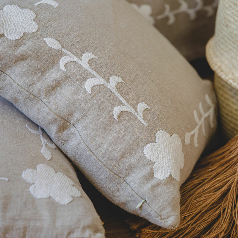 Coussin carré KALOVA en lin beige brodé main de fleurs blanches, style chic et raffiné.