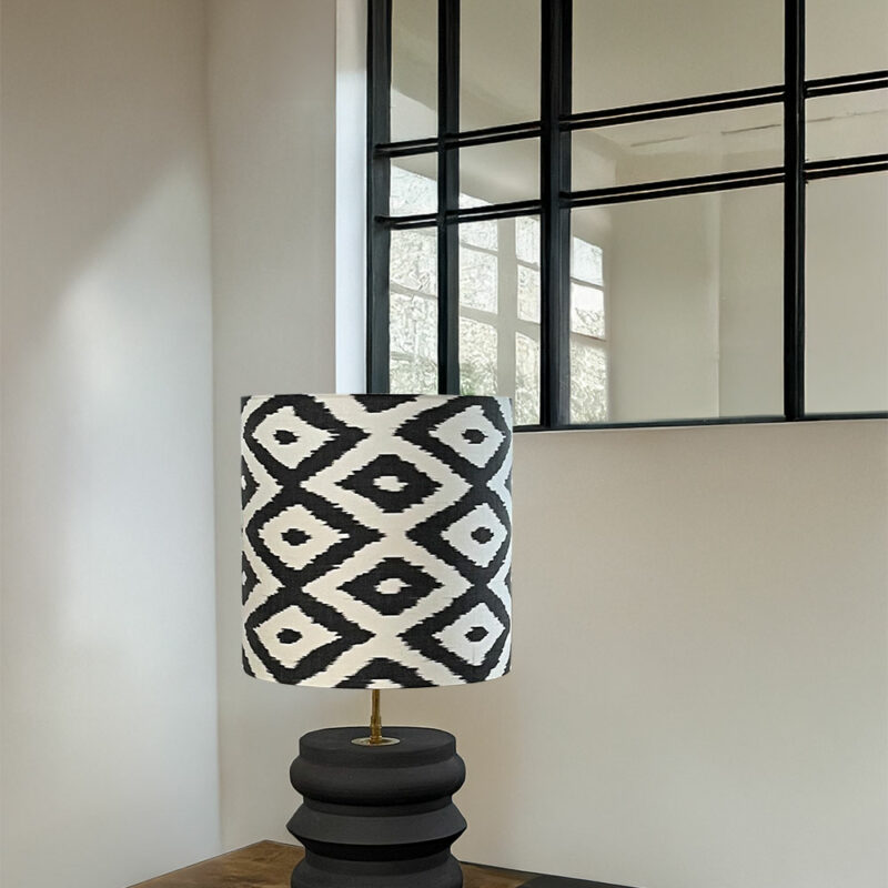 Lampe Noir IKAT pied noir sur bureau, derrière verrière
