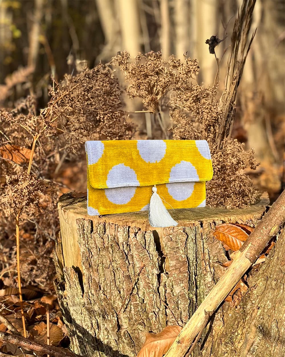 Pochette en velours NIFTY posée sur des feuilles en forêt à l’automne