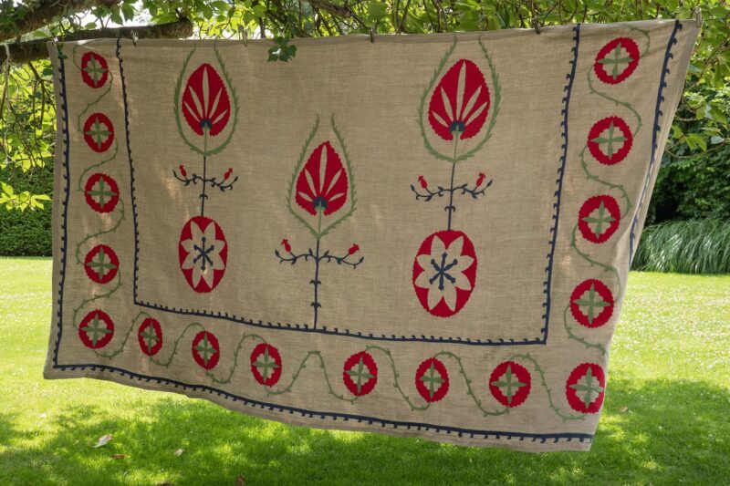 Dessus de lit brodé en lin SABZA étendu dans un jardin – détails des broderies suzani faites main