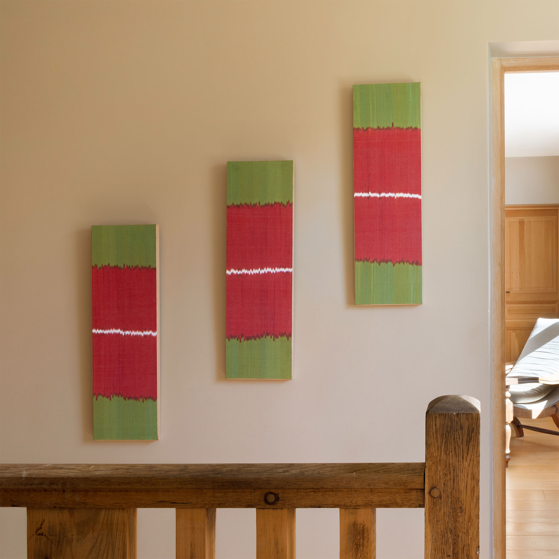 Tableau en tissu ikat accroché sur un mur d’escalier, jeu de textures et de lumière