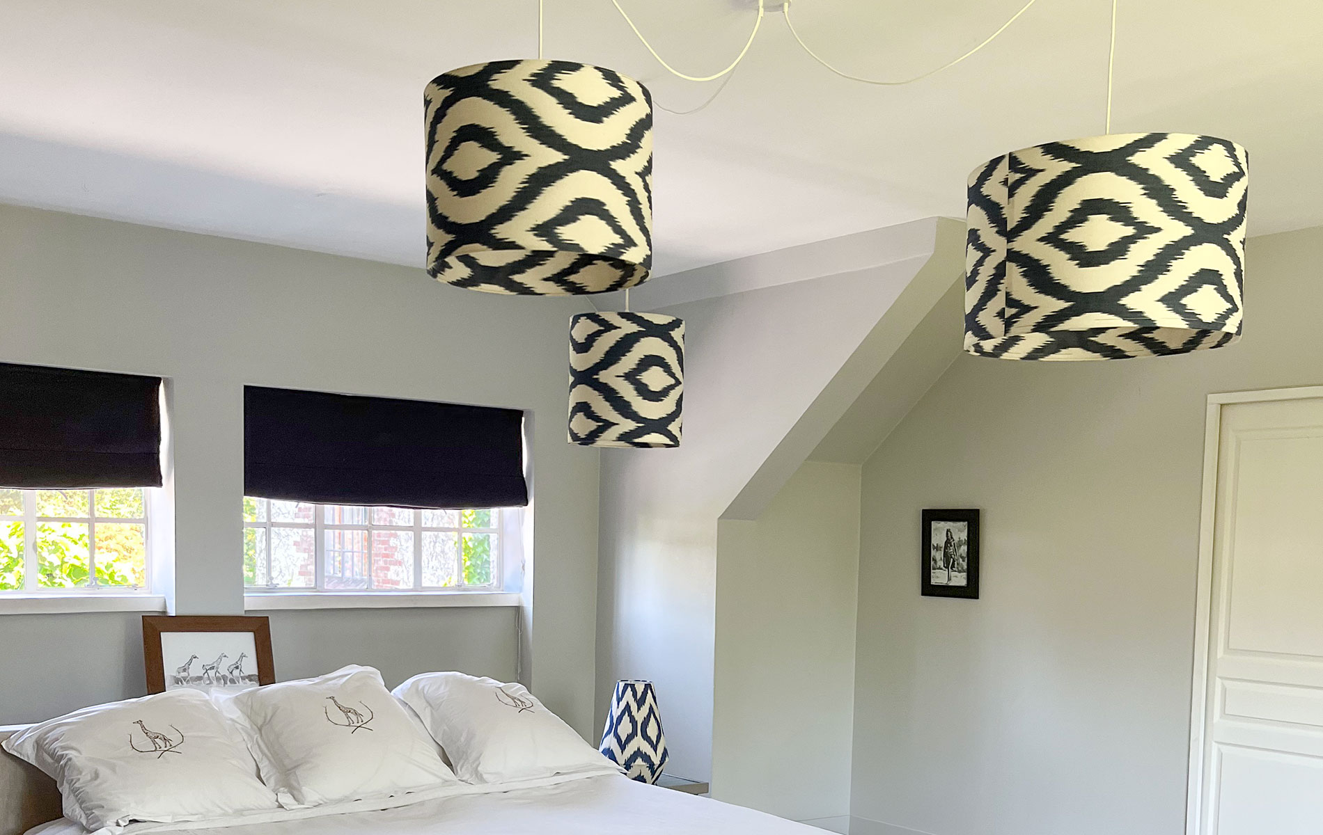 Trio de suspensions luminaires en ikat blanc et bleu dans une chambre élégante.